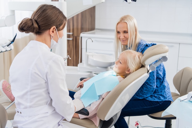 Une dentiste pédiatrique parle à une femme des résultats de l'examen oral de sa fille