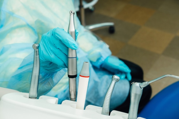 Un dentiste portant des gants dans le cabinet dentaire tient un outil avant de travailler.