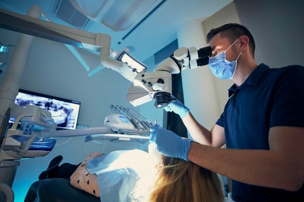 Un dentiste portant un masque examine une fille à la clinique.