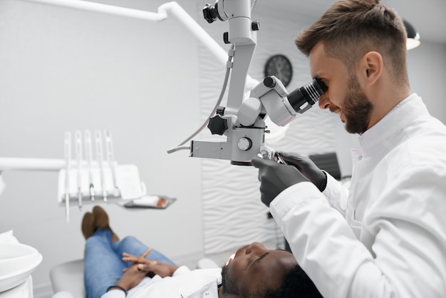 Photo dentiste professionnel gardant l'équipement et examinant les dents