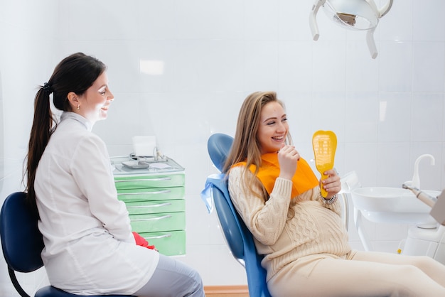 Un dentiste professionnel traite et examine la cavité buccale d'une femme enceinte dans un cabinet dentaire moderne