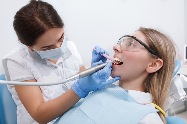 Dentiste professionnel travaillant dans sa clinique, traitant les dents d'une patiente