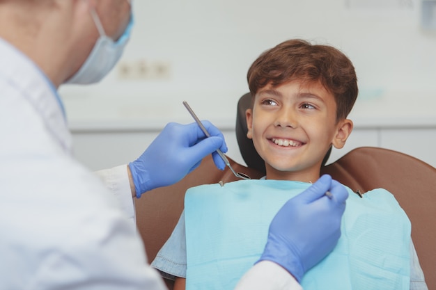 Dentiste professionnel vérifiant les dents d'un beau garçon