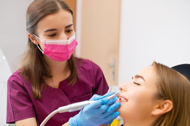 Une dentiste professionnelle effectuant un nettoyage professionnel des dents du patient