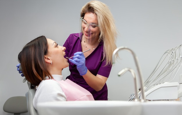 Une dentiste professionnelle examine les dents d'un patient dans une clinique dentaire.