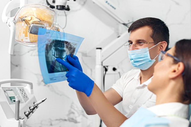 Dentiste regardant une radiographie avec un patient.