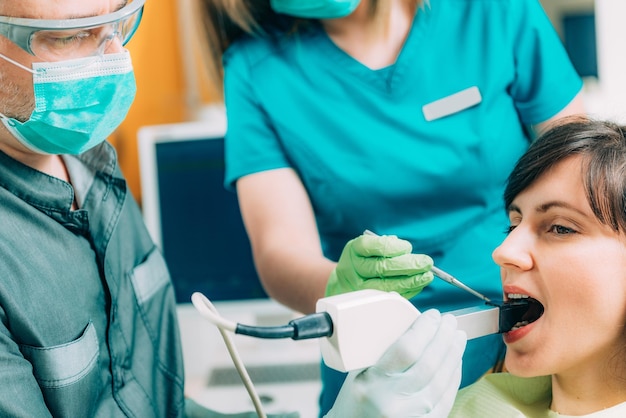 Photo dentiste scannant les dents avec une caméra dentaire