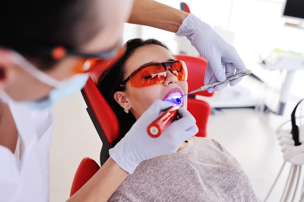 Le dentiste scelle la dent au patient - une jolie jeune fille