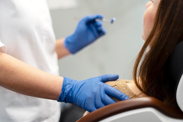 Le dentiste se tient à côté du patient tient un outil dentaire dans sa main libre Concept de travail professionnel cabinet dentaire moderne