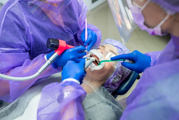 Un dentiste et son assistant effectuent l'opération au cabinet pour poser un implant dentaire.