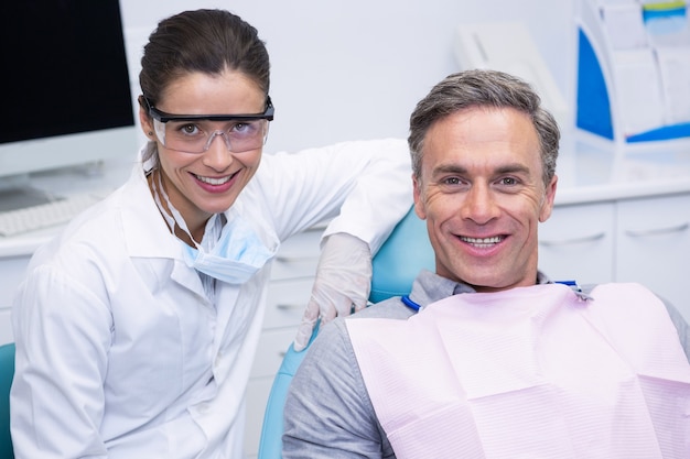 Dentiste souriant par patient à la clinique médicale