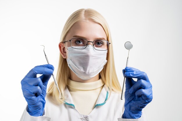 Dentiste tenant un miroir et une sonde isolé sur blanc.