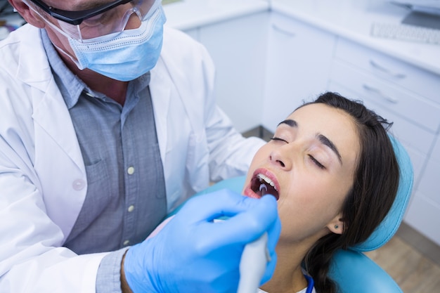 Dentiste tenant des outils tout en traitant la femme à la clinique médicale