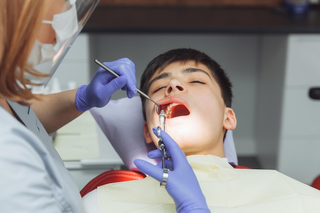 Dentiste en tenue de protection donnant une injection d'anesthésie à un enfant