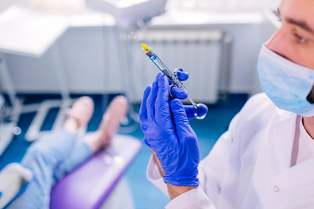 Le dentiste tient une seringue d'anesthésie dans le contexte o