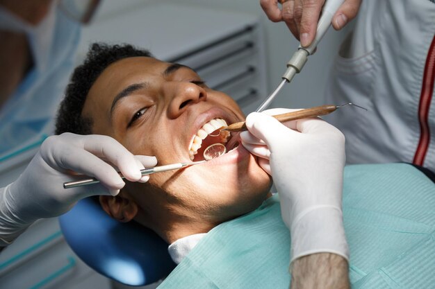 Dentiste traitant un patient masculin dans une clinique
