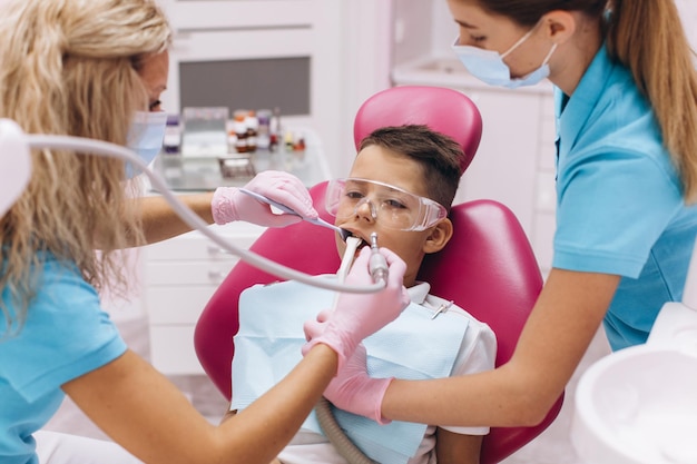 Une dentiste traite les dents d'un garçon dans une clinique dentaire