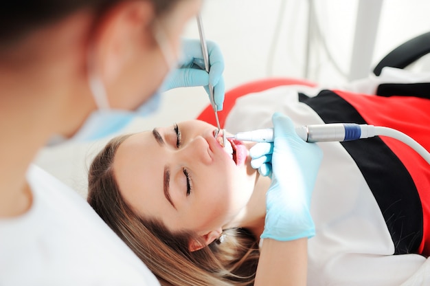 Dentiste traite les dents à un patient - une belle jeune fille