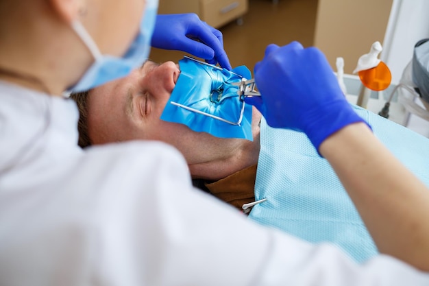 Un dentiste traite un patient de sexe masculin avec des instruments dentaires. Le dentiste examine les dents des patients dans la clinique dentaire. Mise au point sélective