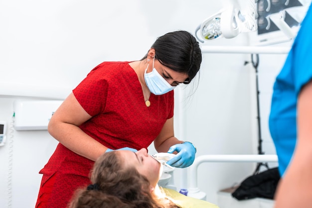 Le dentiste utilise une lampe ultraviolette tout en ajustant la fille avec des accolades