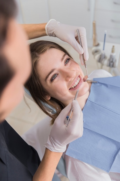 Dentiste vérifiant les dents d'une jeune femme en clinique