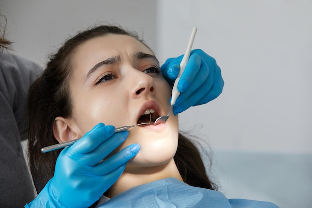 Dentiste vérifiant les dents d'une patiente avec miroir dentaire