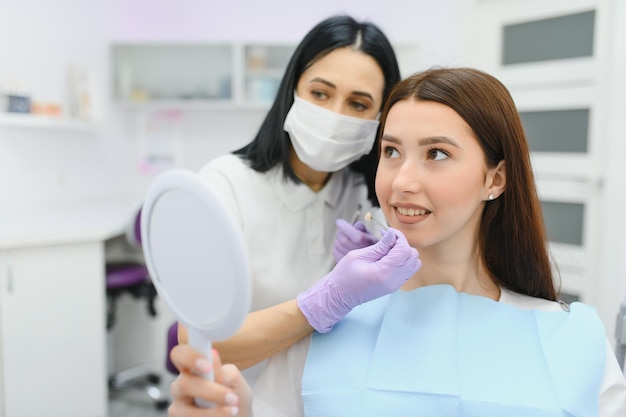 Dentiste vérifiant et sélectionnant la couleur des dents de la jeune femme