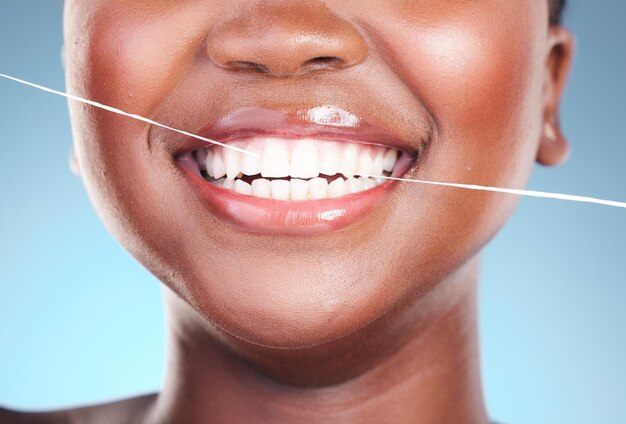 Dents De Femme Heureuse Et Fil Dentaire Dans Le Nettoyage De L'hygiène Ou Des Cosmétiques Sur Fond De Studio Bleu