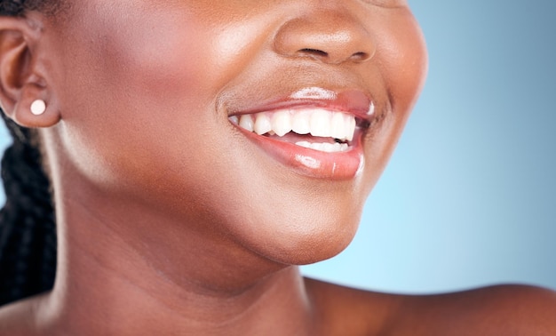 Dents de femme et sourire dans l'hygiène de nettoyage dentaire ou le traitement sur un fond de studio bleu