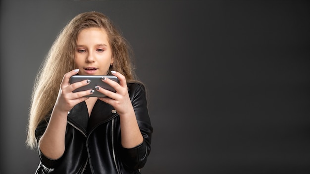 Photo dépendance aux jeux mobiles. divertissement en ligne. adolescente excitée jouant au téléphone