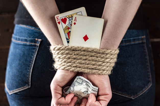 Dépendance à la carte. Dépendance au poker, au jeu. Une jeune femme avec les mains liées tenant des cartes à jouer. Concept de jeu