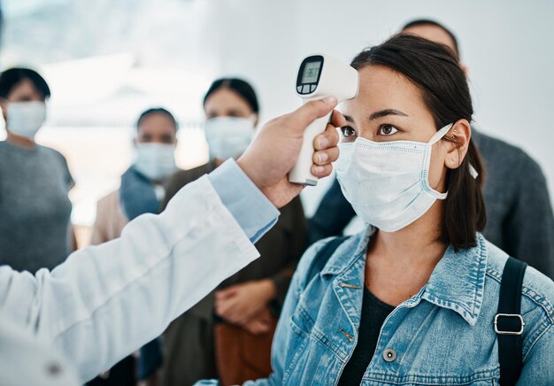 Dépistage Covid avec une touriste portant un masque dont la température est prise avec un thermomètre infrarouge en attendant d'embarquer dans un aéroport Restrictions de voyage pendant la pandémie du virus corona