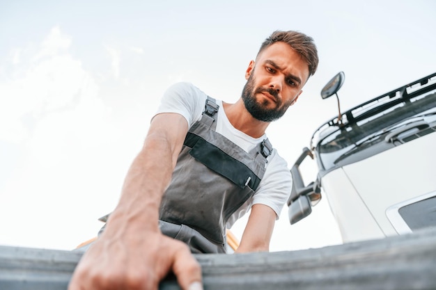 Déplacement d'un pneu cassé Man in unifrom faisant service pour gros camion