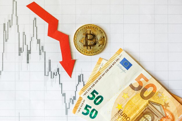 Dépréciation de l'argent virtuel bitcoin Flèche rouge et sur les billets en euros et sur l'arrière-plan de l'index du graphique forex papier Concept de dépréciation de la crypto-monnaie