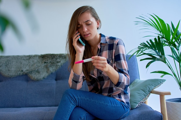 Déprimé triste femme bouleversée confus appelant au téléphone et parler du résultat du test de grossesse