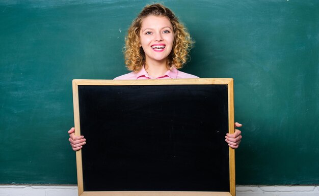 Dernières nouvelles Enseignant femme gaie tenir tableau noir espace copie vierge Concept d'information sur l'école Informations sur le calendrier de la cloche de l'école Rappelez-vous ces informations Informations sur les tâches à domicile Informer les élèves