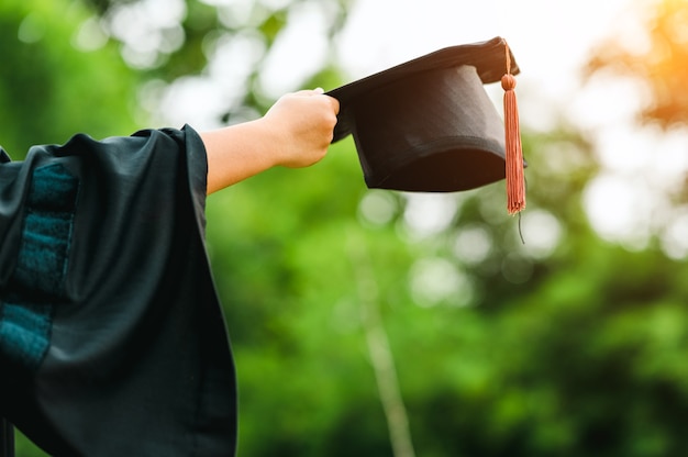 Derrière la photo d'un diplômé universitaire portant une robe et une casquette noire à gland marron