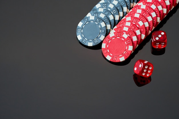 Dés et jetons de casino rouge isolés sur fond réfléchissant noir