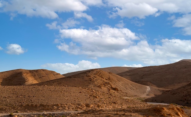 Désert au lever du soleil paysage de montagne avec de la poussière sur les collines de l'horizon et des traces de la voiture tout-terrain un désert de pierre depuis la fenêtre d'une voiture Route ouverte dans le désert vue à travers le pare-brise de la voiture