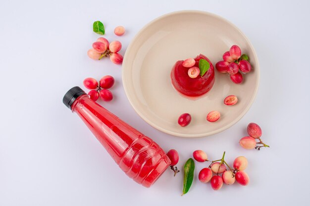 Photo désert à la gelée avec des fruits de carunda ou de karonda biologiques frais sur fond blanc