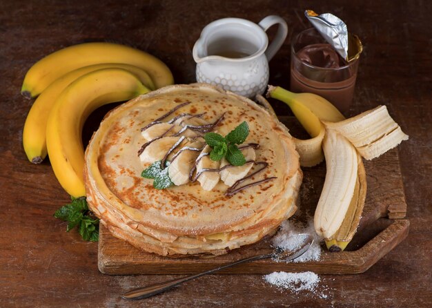 Désert isolé - pile de crêpes au chocolat et banane sur une table en bois