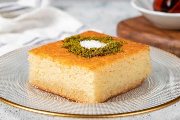 Photo désert de revani gâteau de semoline sucré avec pistache déserts de ramadan délices de la cuisine turque traditionnelle désert de revani avec sirop sur un fond gris en gros