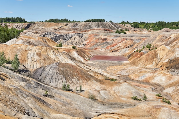 Désert vallonné avec un lac rouge au fond d'un ravin sur le site d'une ancienne carrière d'argile