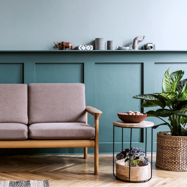 Design d'intérieur élégant du salon dans un appartement confortable avec canapé élégant, plantes, meubles design, décoration et accessoires élégants. Copiez l'espace sur l'étagère. Mise en scène à domicile.