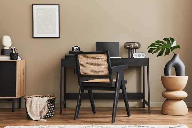 Design d'intérieur moderne de l'espace de bureau à domicile avec chaise élégante, bureau, commode, cadre d'affiche noir, ordinateur portable, livre, organisateur de bureau et accessoires élégants pour la décoration intérieure. Modèle.