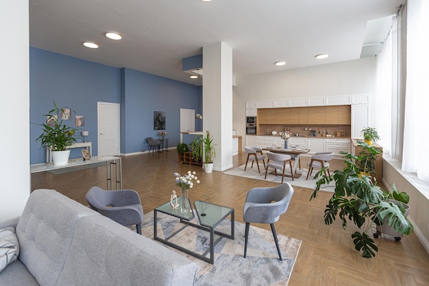 Design d'intérieur moderne minimaliste immense appartement lumineux avec un plan ouvert de style scandinave dans des couleurs bleu blanc et bleu foncé avec des colonnes au centre comprend un coin cuisine bureau et salon