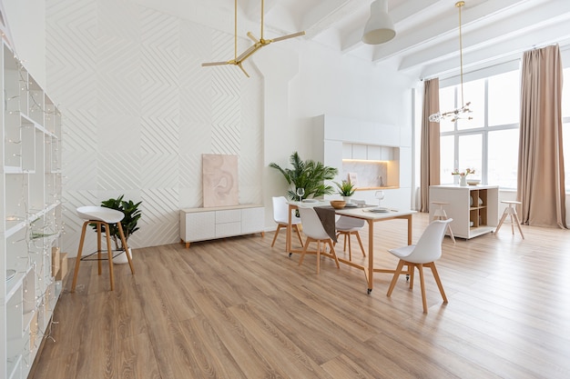 Design d'intérieur spacieux appartement lumineux dans un style scandinave et des tons blancs et beiges pastel chaleureux. mobilier tendance dans le salon et détails modernes dans le coin cuisine.