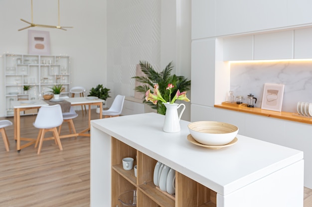 Design d'intérieur spacieux appartement lumineux dans un style scandinave et des tons blancs et beiges pastel chaleureux. mobilier tendance dans le salon et détails modernes dans le coin cuisine.