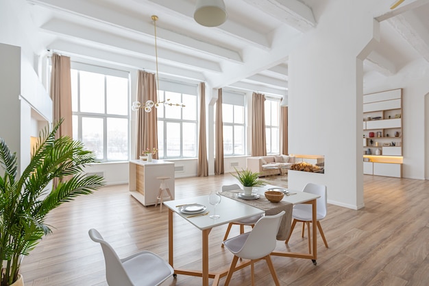 Design d'intérieur spacieux appartement lumineux dans un style scandinave et des tons blancs et beiges pastel chaleureux. mobilier tendance dans le salon et détails modernes dans le coin cuisine.