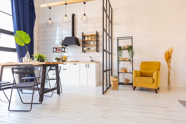 Design moderne de luxe d'un petit studio confortable de style scandinave avec des murs blancs, au deuxième étage avec une bibliothèque et une grande fenêtre haute pleine de lumière du jour